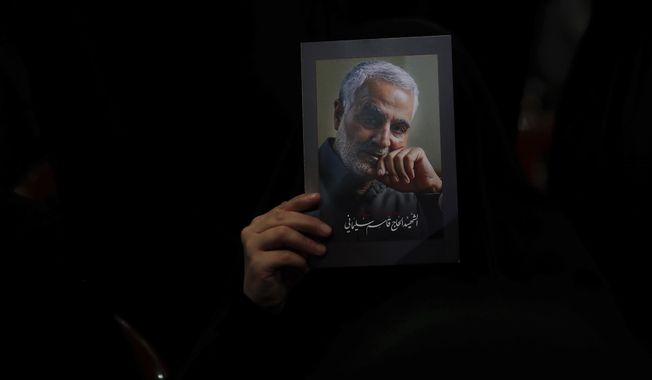 A Hezbollah supporter holds pictures of slain Iranian Revolutionary Guard Gen. Qassem Soleimani during a ceremony marking the anniversary of the assassination of Hezbollah leaders, Abbas al-Moussawi, Ragheb Harb and Imad Mughniyeh and the end of a 40-day Muslim mourning period for Soleimani, in the southern suburb of Beirut, Lebanon, Sunday, Feb. 16, 2020. Nasrallah said U.S. President Donald Trump declared war on the Middle East when the U.S. assassinated Soleimani and when the White House announced its plan to end the Palestinian-Israeli conflict. He called on all to resist U.S. influence and its troops presence. (AP Photo/Hassan Ammar)