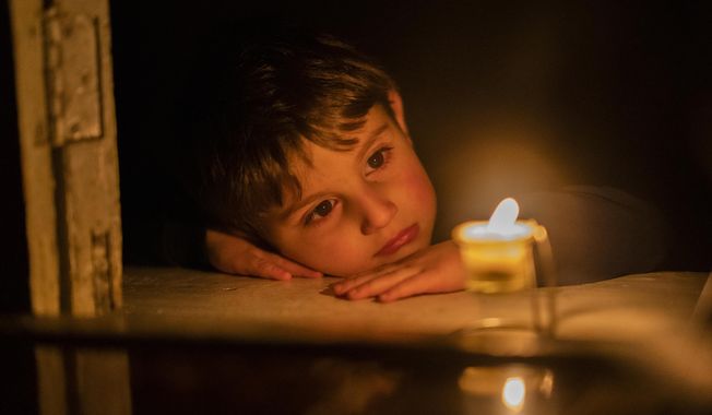 A boy looks at a candle trying to warm himself at home in Stepanakert, the capital of the separatist region of Nagorno-Karabakh, also known as Artsakh, on Wednesday, Jan. 18, 2023. In the region have been periodic shutoffs of gas and electricity to the region during the dispute. Protesters claiming to be ecological activists have blocked the only road leading from Armenia to Nagorno-Karabakh for more than a month, leading to increasing food shortages. (Edgar Harutyunyan/PAN Photo via AP)
