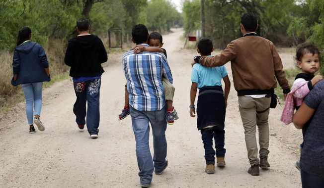 In this file photo, a group of migrant families walk from the Rio Grande, the river separating the U.S. and Mexico in Texas, near McAllen, Texas, on March 14, 2019. (AP Photo/Eric Gay, File)