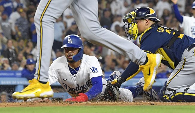 Los Angeles Dodgers&#x27; Mookie Betts, center, scores on a double by Freddie Freeman as Milwaukee Brewers catcher William Contreras, right, puts a late tag on him while relief pitcher Abner Uribe backs up the play during the sixth inning of a baseball game Wednesday, Aug. 16, 2023, in Los Angeles. (AP Photo/Mark J. Terrill)