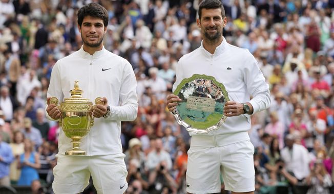 Spain&#x27;s Carlos Alcaraz, left, celebrates with the trophy after beating Serbia&#x27;s Novak Djokovic, right, to win the final of the men&#x27;s singles on day fourteen of the Wimbledon tennis championships in London, Sunday, July 16, 2023. (AP Photo/Kirsty Wigglesworth)