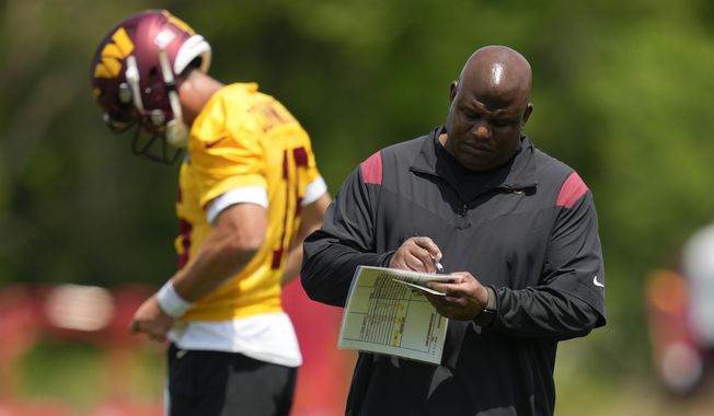 Washington Commanders assistant head coach/offensive coordinator Eric Bieniemy looks over a play card during the NFL football team&#x27;s rookie minicamp, Friday, May 12, 2023, in Ashburn, Va. (AP Photo/Patrick Semansky)