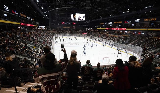 Fans watch as players warm up prior to the Arizona Coyotes&#x27; home-opening NHL hockey game against the Winnipeg Jets at the 5,000-seat Mullett Arena in Tempe, Ariz., Oct. 28, 2022. The Coyotes say owner Alex Meruelo has executed a letter of intent to buy a piece of land for a potential arena in Mesa, Arizona. The move comes months after voters in Tempe rejected a referendum to construct an arena there for the NHL club. (AP Photo/Ross D. Franklin, File)
