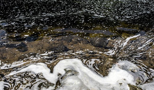 FILE - PFAS foam gathers at the the Van Etten Creek dam in Oscoda Township, Mich., near Wurtsmith Air Force Base on June 7, 2018. Groundwater treatment systems will be installed near a military base in northern Michigan to address contamination from high levels of toxic, widely used “forever chemicals,” the U.S. Department of Defense announced Thursday, Aug. 17, 2023. (Jake May/The Flint Journal via AP, File)