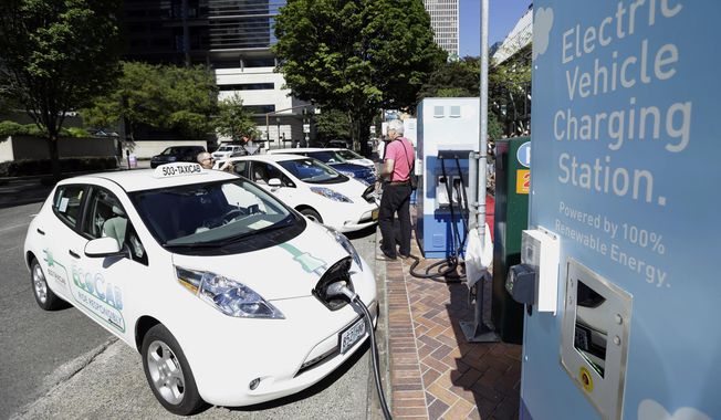 FILE - A line of electric cars and newly installed charging stations sit in front of the Portland General Electric headquarters building on July 28, 2015, in Portland, Ore. Policymakers for the Oregon Department of Environmental Quality on Monday, Dec. 19, 2022, approved a rule that prohibits the sale of new gasoline-powered passenger vehicles in Oregon by 2035. (AP Photo/Don Ryan, File)