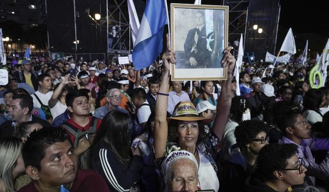 Supporters hold a photo or former Guatemalan President Juan Jose Arevalo as they listen to his son Bernardo, current presidential candidate with Seed Movement party, during his closing campaign rally at Constitution square in Guatemala City, Wednesday, Aug. 16, 2023. Arevalo faces rival and former first lady Sandra Torres of the UNE party in the Aug. 20 runoff election. (AP Photo/Moises Castillo)