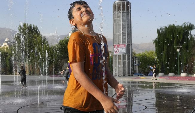 A young boy cools off in a water fountain at the Ebrahim Park while temperature reaches 38 C (100.4 F) in Tehran, Iran, Tuesday, Aug. 1, 2023. Iran announced a nationwide two-day, Wednesday and Thursday, holiday because of increasing temperatures. (AP Photo/Vahid Salemi)