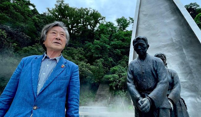 Song Seung-moon stands in front of a memorial to the victims of the carnage of 1948-49: a statue of islanders, their hands bound, being led away to their deaths. (Andrew Salmon/The Washington Times)