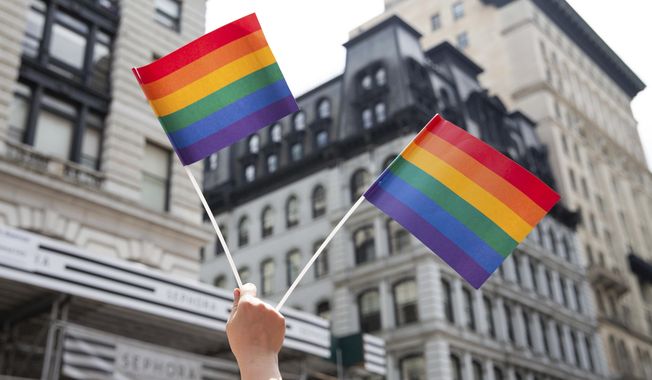 An attendee holds up flags during the New York City Pride Parade, June 24, 2018, in New York. (AP Photo/Steve Luciano, File)
