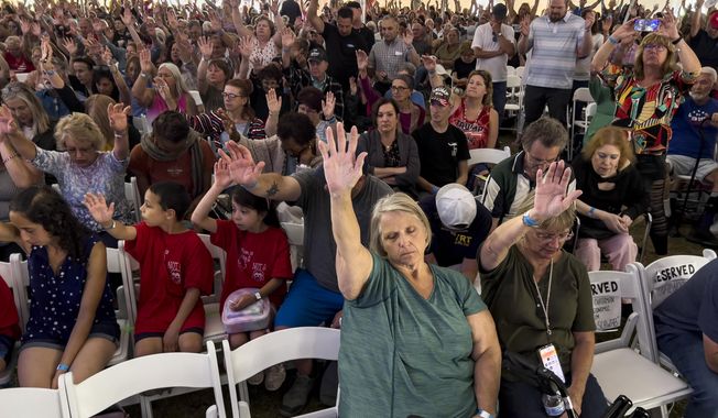 Attendees raise their hands as they worship inside the tent during the ReAwaken America tour at Cornerstone Church, in Batavia, N.Y., Friday, Aug. 12, 2022. Speaking at the event, Michael Flynn, former national security adviser to former President Donald Trump, is trying to build a movement centered on Christian nationalist ideas, where Christianity is at the center of American life and institutions. (AP Photo/Carolyn Kaster) **FILE**
