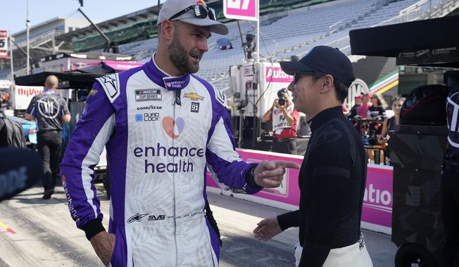 Shane van Gisbergen, left, and Kamui Kobayashi talk before a practice session for the NASCAR Cup Series auto race at Indianapolis Motor Speedway, Saturday, Aug. 12, 2023, in Indianapolis. (AP Photo/Darron Cummings)