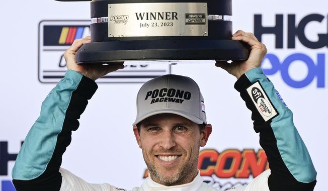 Denny Hamlin poses with the trophy in Victory Lane after winning a NASCAR Cup Series auto race at Pocono Raceway, Sunday, July 23, 2023, in Long Pond, Pa. (AP Photo/Derik Hamilton)