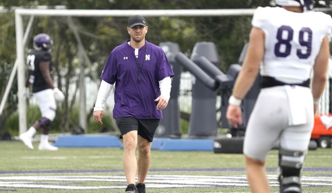 Northwestern interim head coach David Braun, center, walks on the field as he watches players during team&#x27;s practice in Evanston, Ill., Wednesday, Aug. 9, 2023. (AP Photo/Nam Y. Huh)