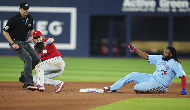 Toronto Blue Jays&#x27; Vladimir Guerrero Jr. slides into second base on a steal attempt as Philadelphia Phillies second baseman Bryson Stott catches the throw during the fifth inning of a baseball game Wednesday, Aug. 16, 2023, in Toronto. Guerrero was called out. (Nathan Denette/The Canadian Press via AP)