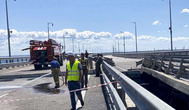 In this image from a video released on Wednesday, July 19, 2023 by Russian National Antiterrorism Committee, employees work at the damaged parts of an automobile link of the Crimean Bridge connecting Russian mainland and Crimean peninsula over the Kerch Strait not far from Kerch, Crimea. (Russian National Antiterrorism Committee via AP)