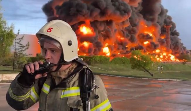 In this handout photo made from video released by the Governor of Sevastopol Mikhail Razvozhaev telegram channel on Saturday, April 29, 2023, a firefighter speaks on the walkie-talkie as smoke and flame rise from a burning fuel tank after it was hit by a drone, a Russian-appointed official there reported, in Sevastopol, Crimea. The Crimean Peninsula&#x27;s balmy beaches have been vacation spots for Russian czars and has hosted history-shaking meetings of world leaders. And it has been the site of ethnic persecutions, forced deportations and political repression. Now, as Russia’s war in Ukraine enters its 18th month, the Black Sea peninsula is again both a playground and a battleground. (Sevastopol Governor Mikhail Razvozhaev telegram channel via AP) **FILE**
