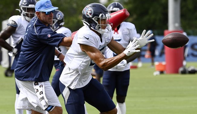 Tennessee Titans wide receiver Treylon Burks makes a catch as head coach Mike Vrabel hits him with an arm pad during an NFL football training camp practice Tuesday, Aug. 8, 2023, in Nashville, Tenn. (Mark Zaleski/The Tennessean via AP)