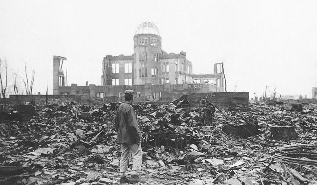 In this 1945 file photo, an Allied war correspondent stands in the ruins of Hiroshima, Japan, just weeks after the city was leveled by an atomic bomb. Many residents of Hiroshima welcome attention to their city from abroad, which IOC President Thomas Bach will bring when he visits on Friday, July 16. But Bach will also bring political baggage — as will his vice president John Coates when he visits Nagasaki the same day — that is largely unwelcome in two cities viewed as sacred by many Japanese. (AP Photo/File)