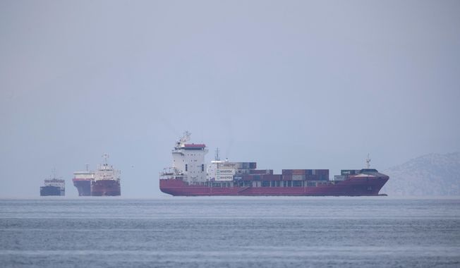 A cargo ship approaches the port of Piraeus as other ships are anchored, near Athens, Greece in this May 26, 2020 file photo. The United Nations is trying to figure out how to help more than 300,000 merchant mariners trapped at sea because of COVID-19 virus restrictions that they face when they get home. Describing the desperation of seafarers who&#x27;ve been afloat for a year or more, Captain Hedi Marzougui pleaded their case Thursday, Sept. 24, 2020 at a U.N.-organized meeting with shipping executives and government transport officials.(AP Photo/Petros Giannakouris, File)